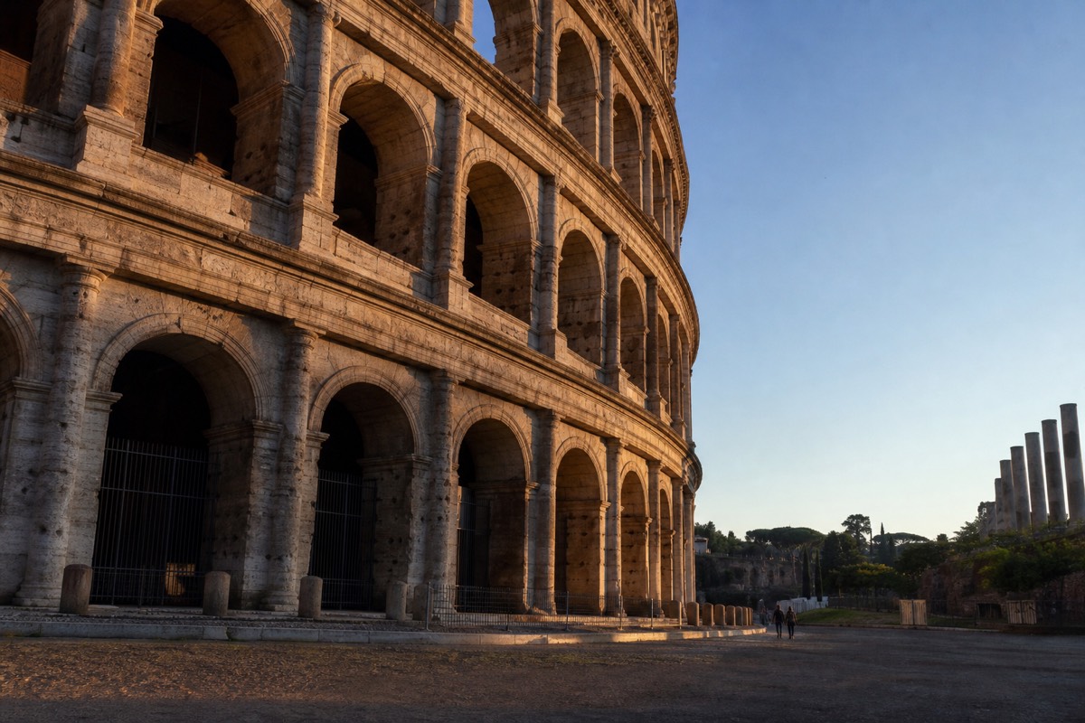 The Colosseum lit by early-morning sun, seen from the Oppian Hill in Rome
